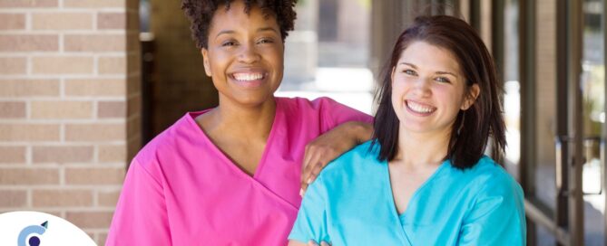 2 caregivers smile representing the good attitude that can allow home care professionals to collaborate.