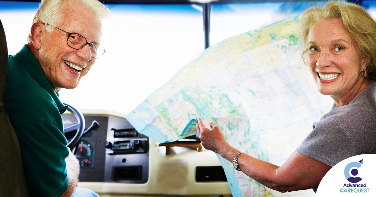 An older couple looks back smiling from the front of an RV, representing how day trips for seniors can help boost the mood of everyone.