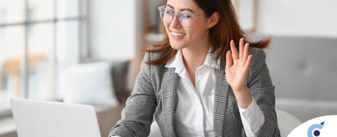 A well-dressed woman smiles and says hi on a videoconference, representing a candidate who is well-prepared for a caregiver interview.