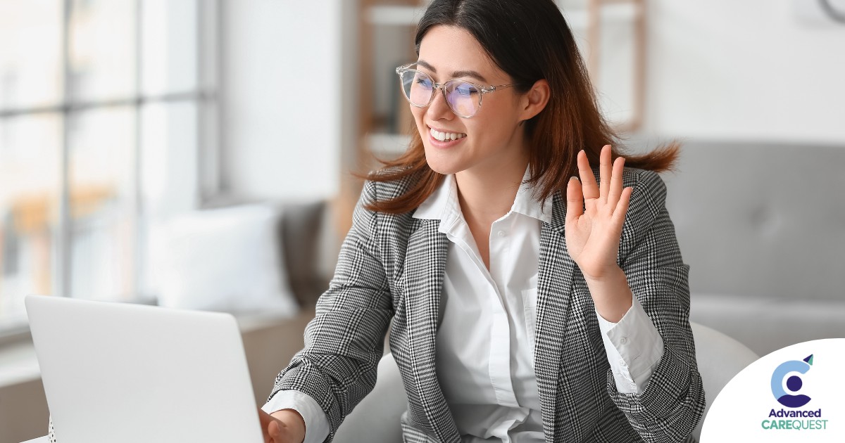 A well-dressed woman smiles and says hi on a videoconference, representing a candidate who is well-prepared for a caregiver interview.
