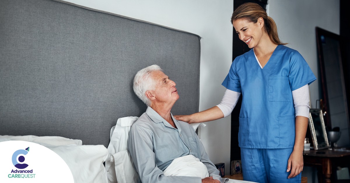 A caregiver smiles at an older client in bed, representing the compassion involved in being a live-in caregiver.