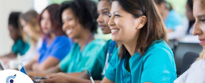 Several students in scrubs happily attend a class, representing caregiver training.