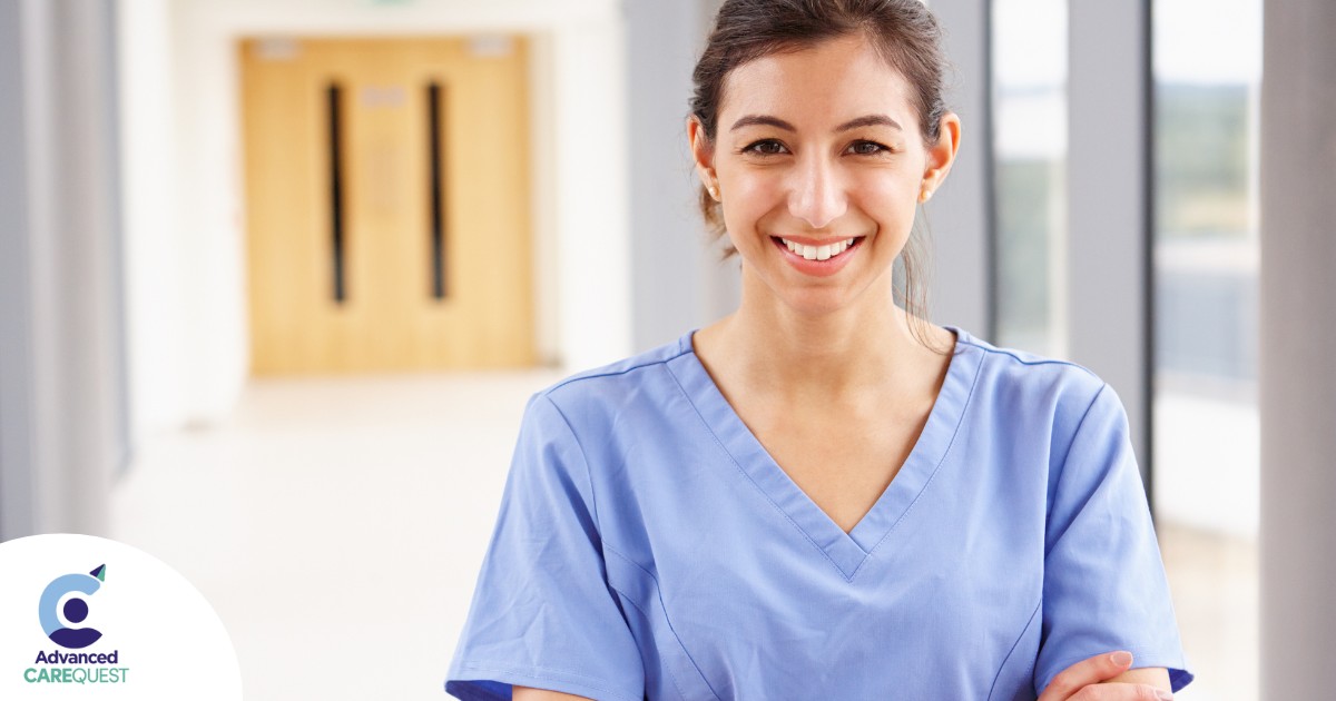 A woman in scrubs smiles, representing the good results that can come when caregivers branch out to become CNAs.