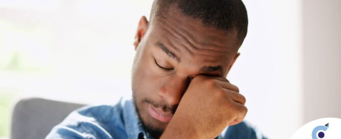 A man tiredly rubs his eyes, representing the exhaustion that can come with family caregiving.